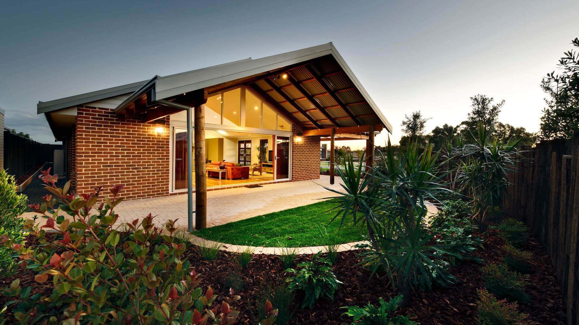 brick home with patio and manicured gardens