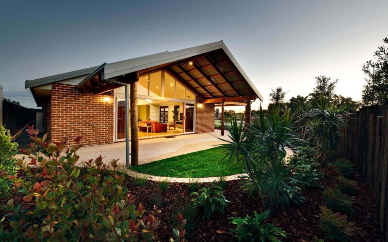 brick home with patio and manicured gardens