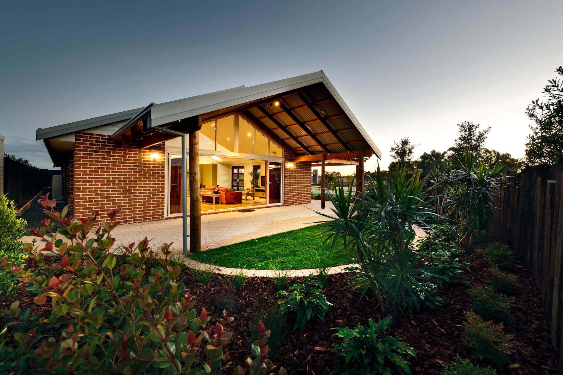 brick home with patio and manicured gardens