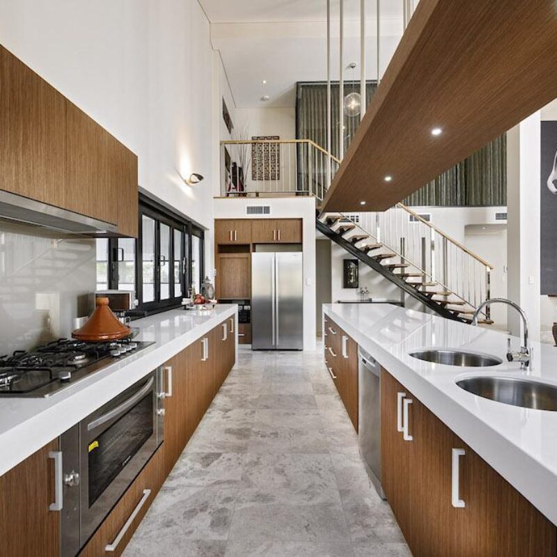 Galley kitchen with timber overhead cabinetry and stainless steel appliances