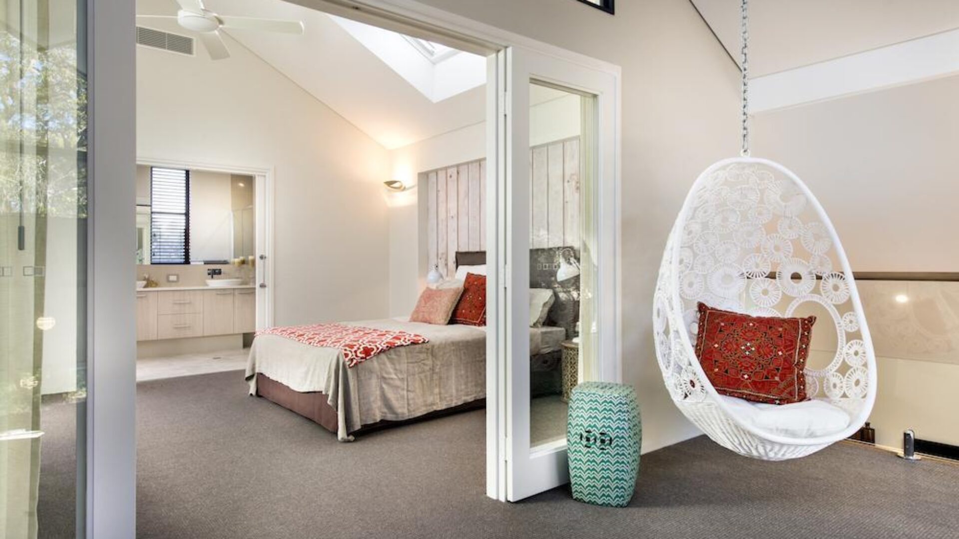 Bedroom with hanging egg chair and ensuite beyond