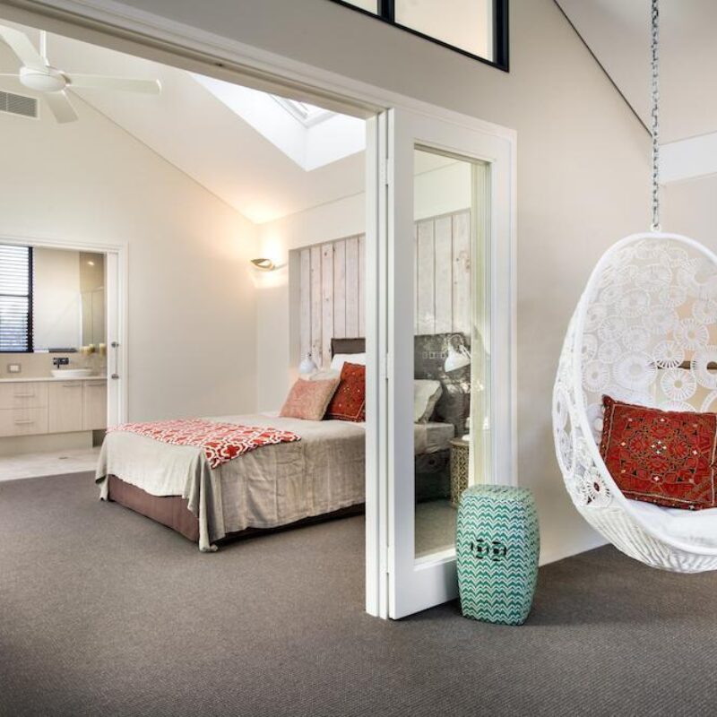 Bedroom with hanging egg chair and ensuite beyond