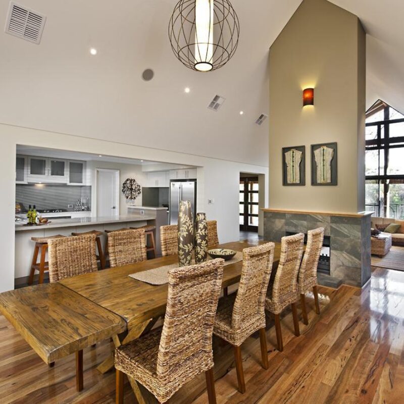 Dining area with long timber table, wicker chairs and stone fireplace