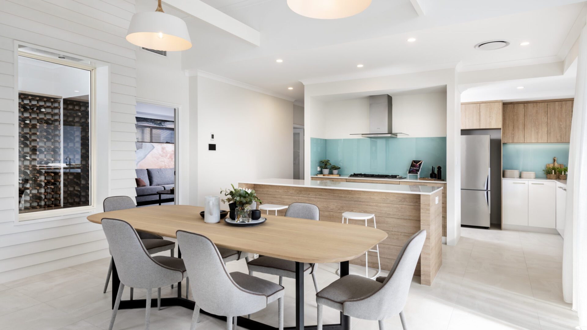 open plan kitchen with aqua splash back and wooden dining table