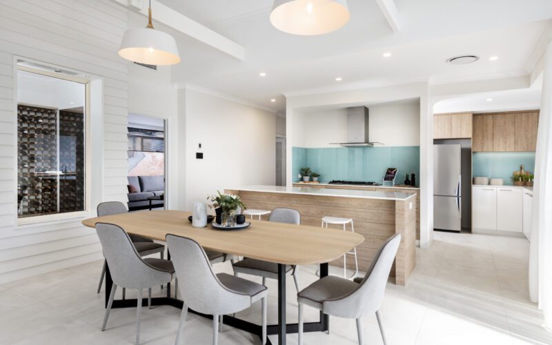 open plan kitchen with aqua splash back and wooden dining table