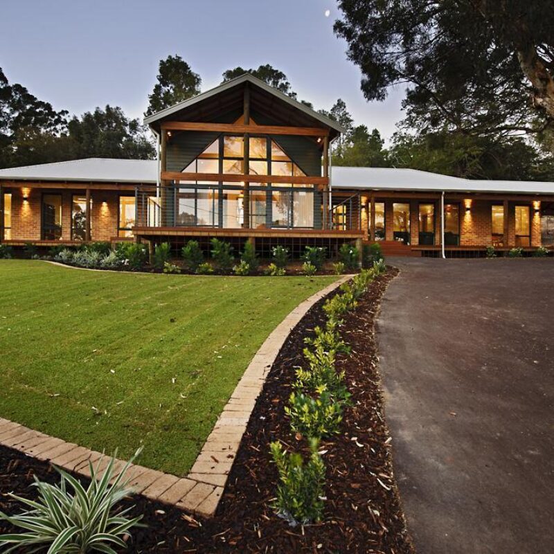 Single storey home with gable glazing, wraparound verandah and curved driveway