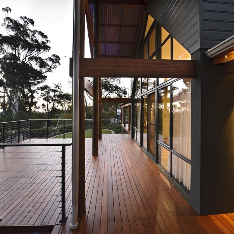Timber decked verandah running along a home with steel balustrade and bush outlook