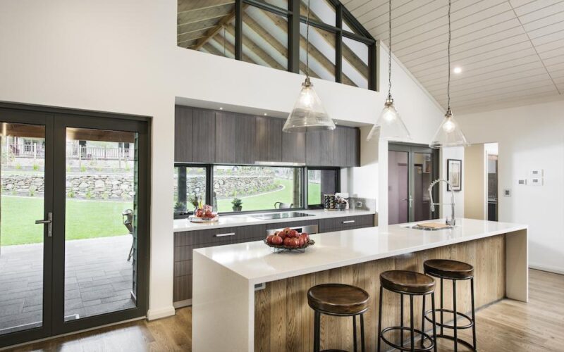 Kitchen with white stone island bench, glass pendant lights and rural outlook