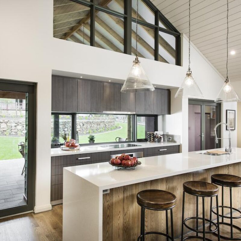 Kitchen with white stone island bench, glass pendant lights and rural outlook