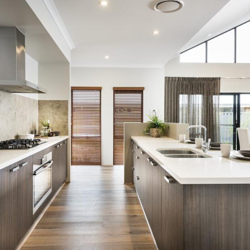 Kitchen with stone island bench, raked ceiling and dining area beyond
