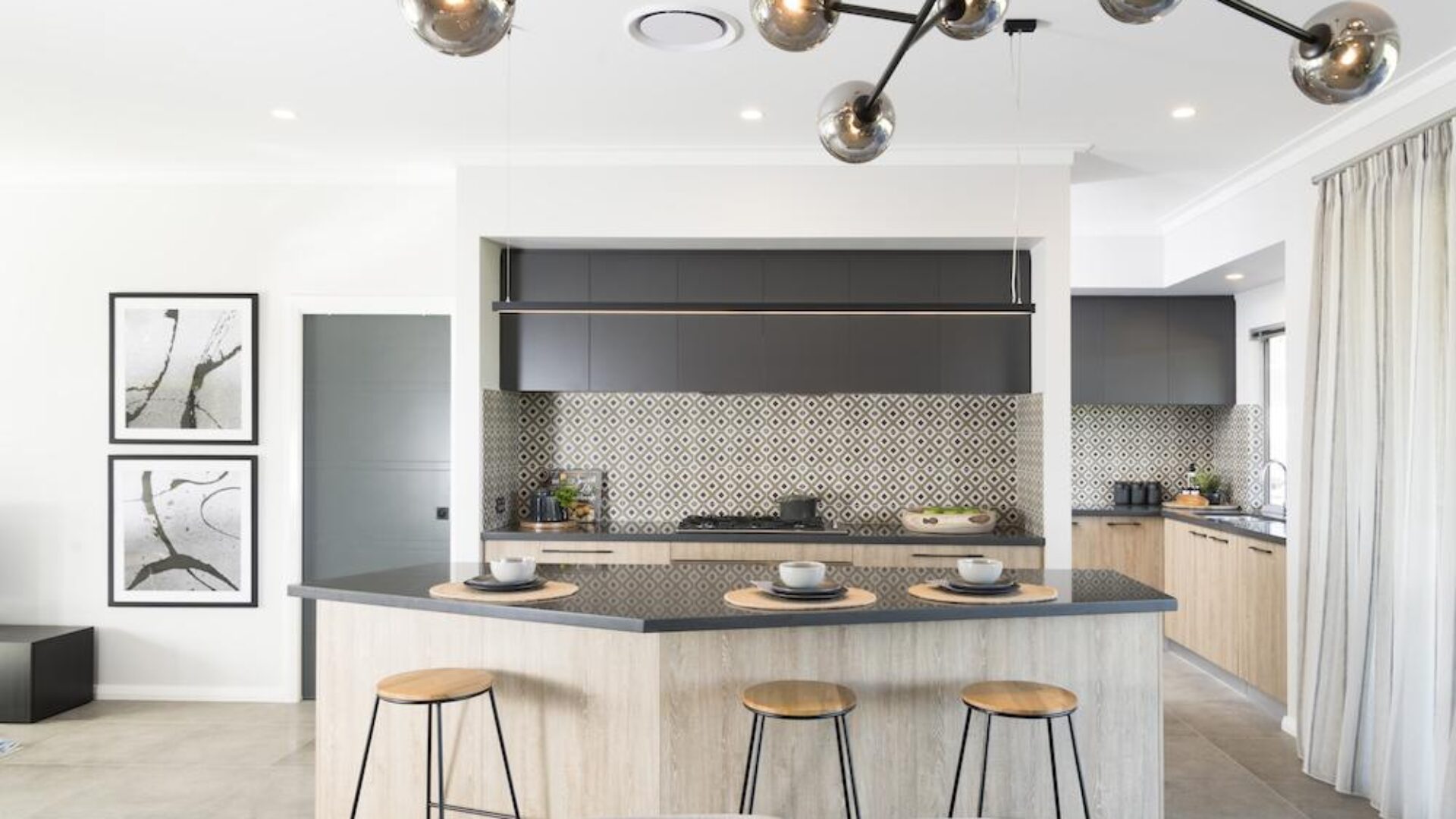 Kitchen with grey stone island bench, herringbone splashback and timber stools