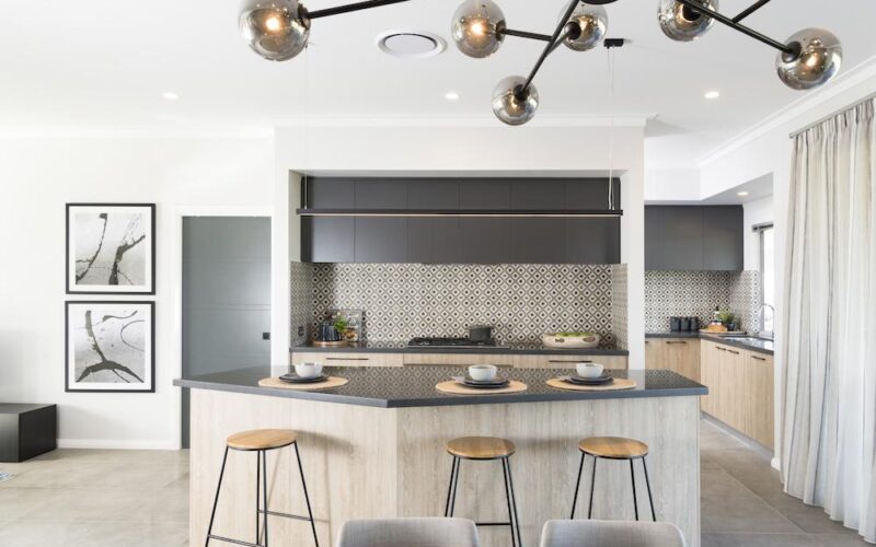 Kitchen with grey stone island bench, herringbone splashback and timber stools