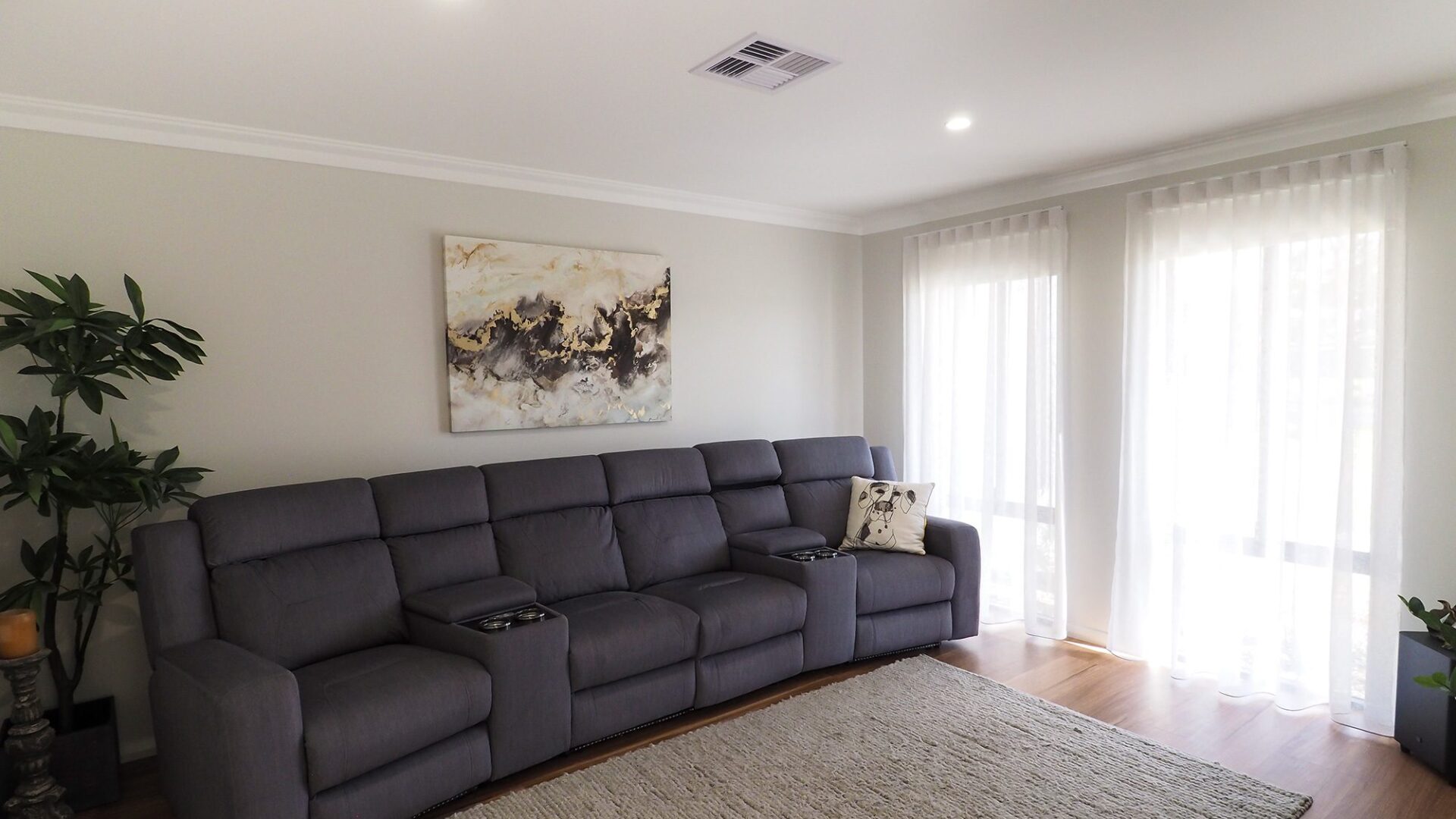 Living area with grey modular recliner lounge and woven rug