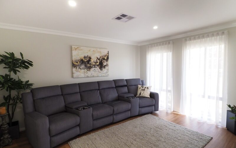 Living area with grey modular recliner lounge and woven rug