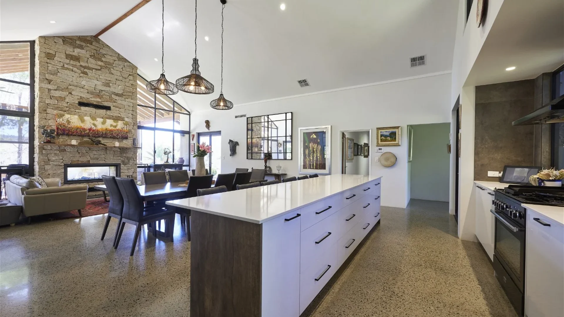 Kitchen and dining with stone fireplace, raked ceiling and polished concrete floor