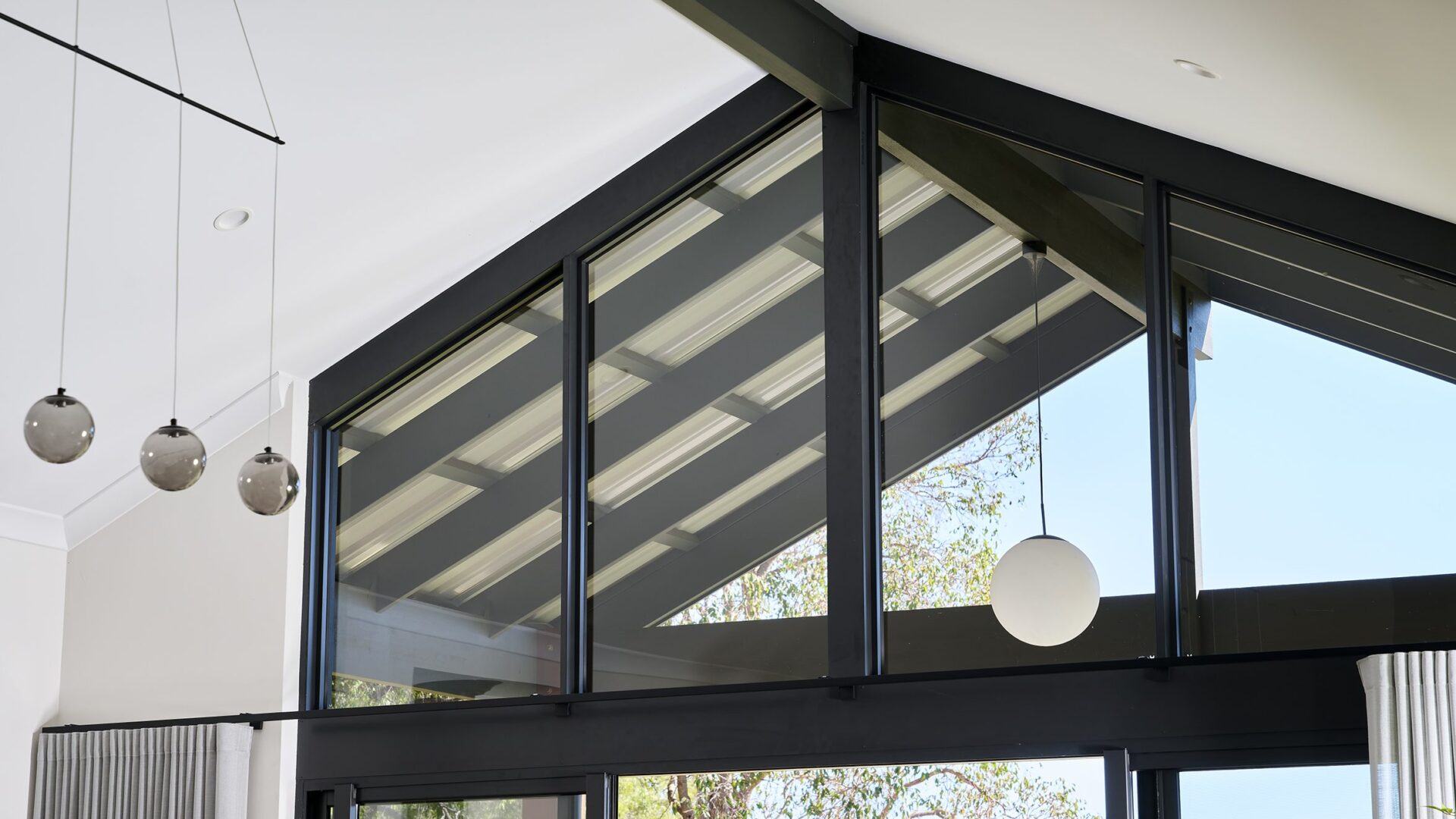 Gable glazing detail with black frames and pendant lights