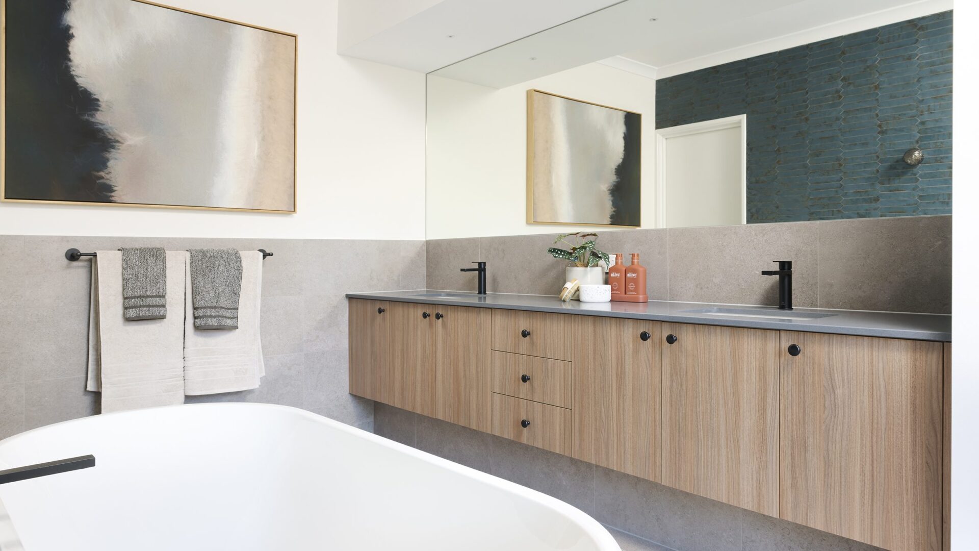 Bathroom with timber vanity, freestanding bath and framed artwork