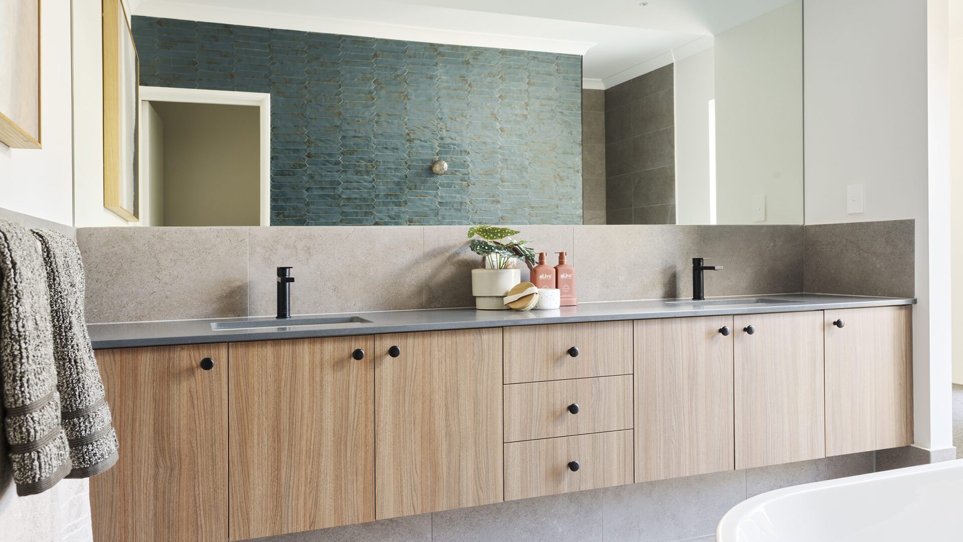 Bathroom with timber vanity, twin basins and green tiled feature wall