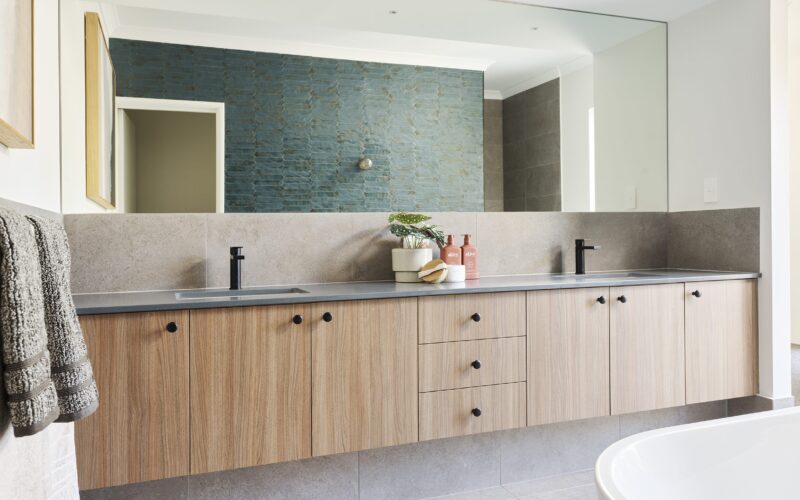 Bathroom with timber vanity, twin basins and green tiled feature wall