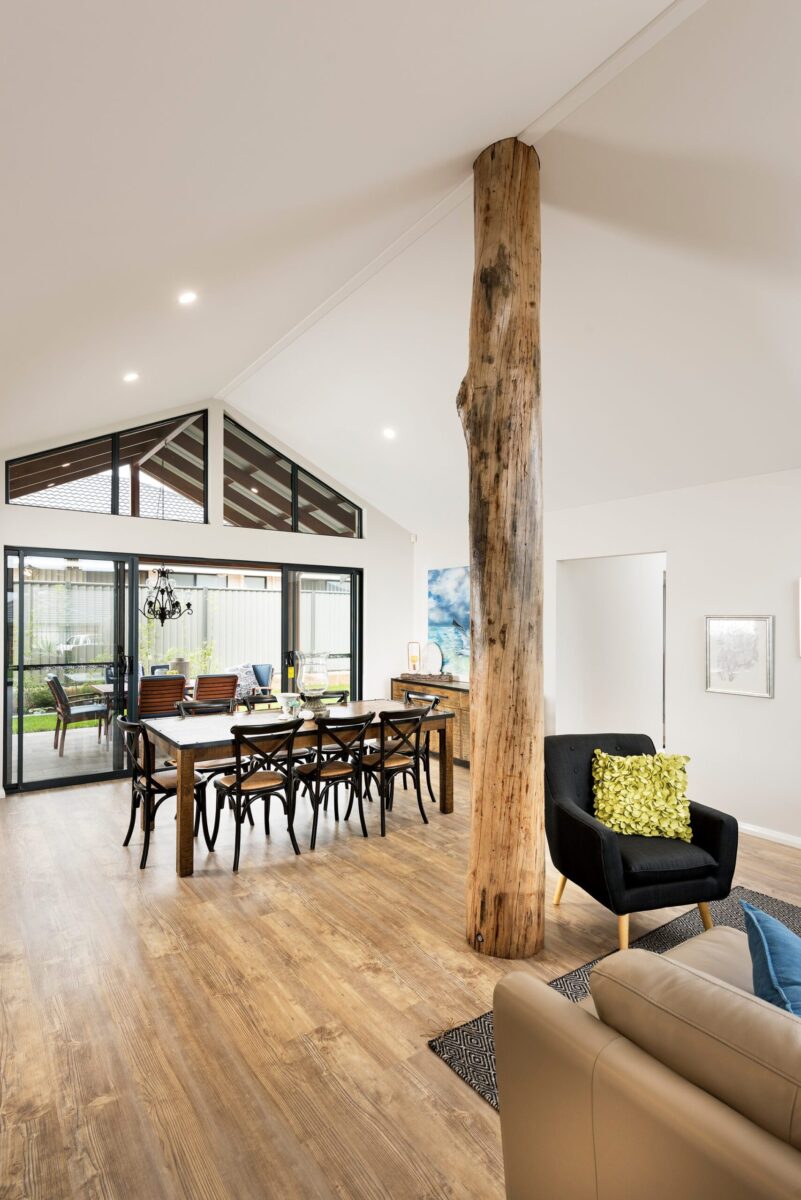 Living and dining with raked ceiling, timber pole and full height glazing