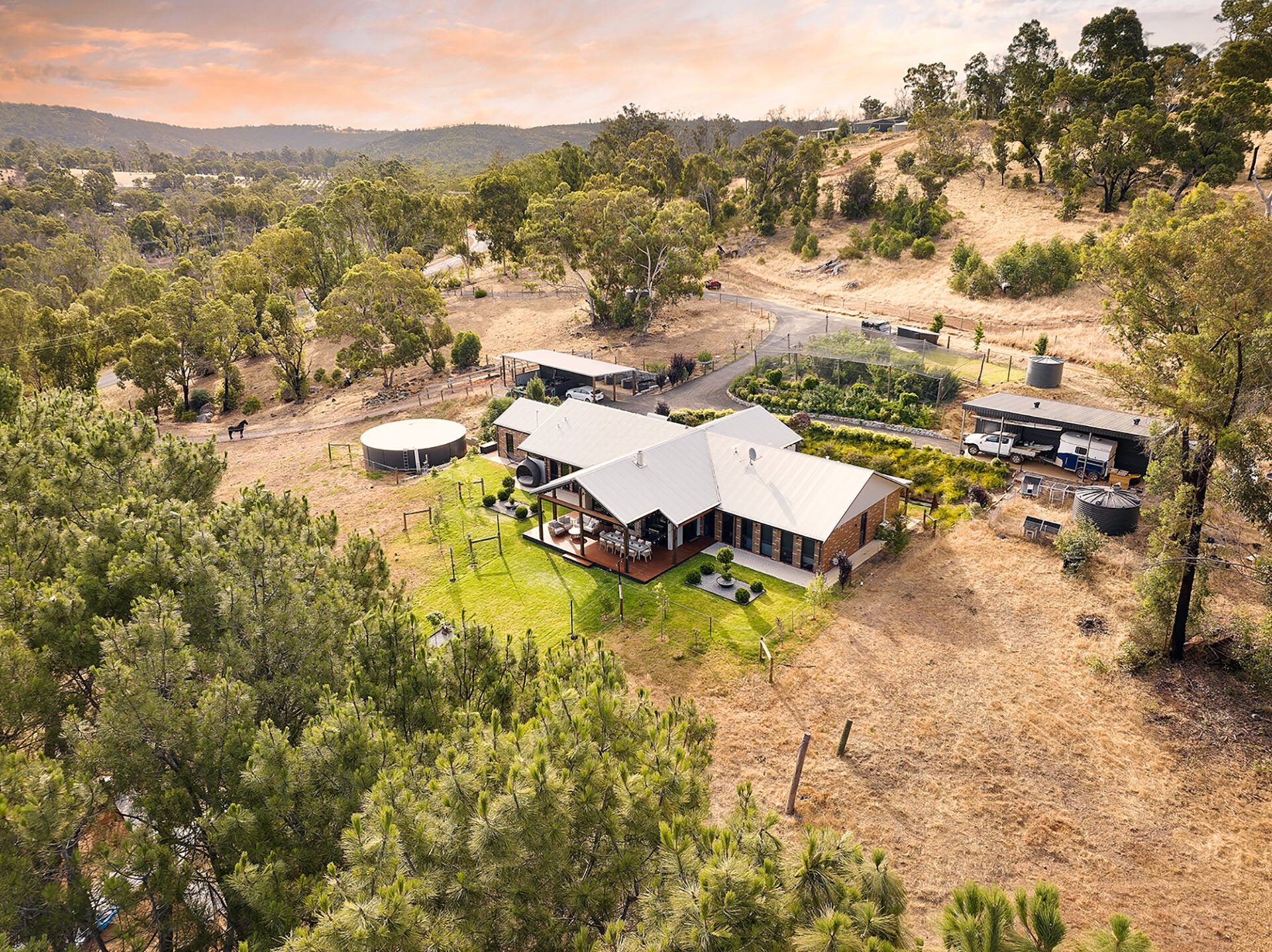 Aerial view of a modern rural residential property with large verandas, lawn, and surrounding bushland.