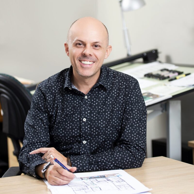 Portrait of Rob at a desk with building plans