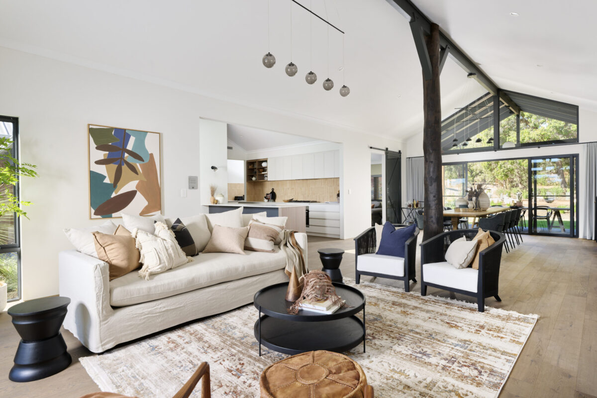 Open plan living with raked ceiling, exposed timber truss and cream lounge suite
