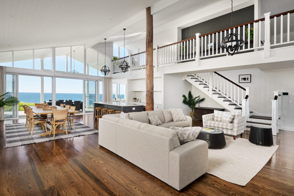 Two storey living area with white balustrade, timber flooring and ocean views