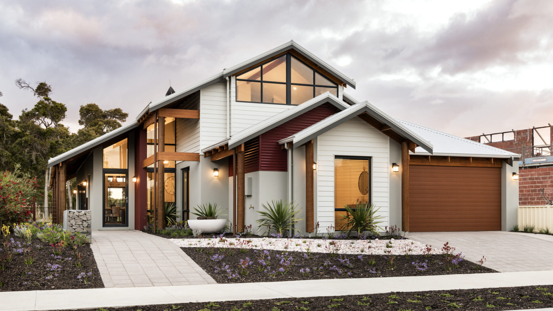 Two storey weatherboard home with gable glazing and landscaped garden beds