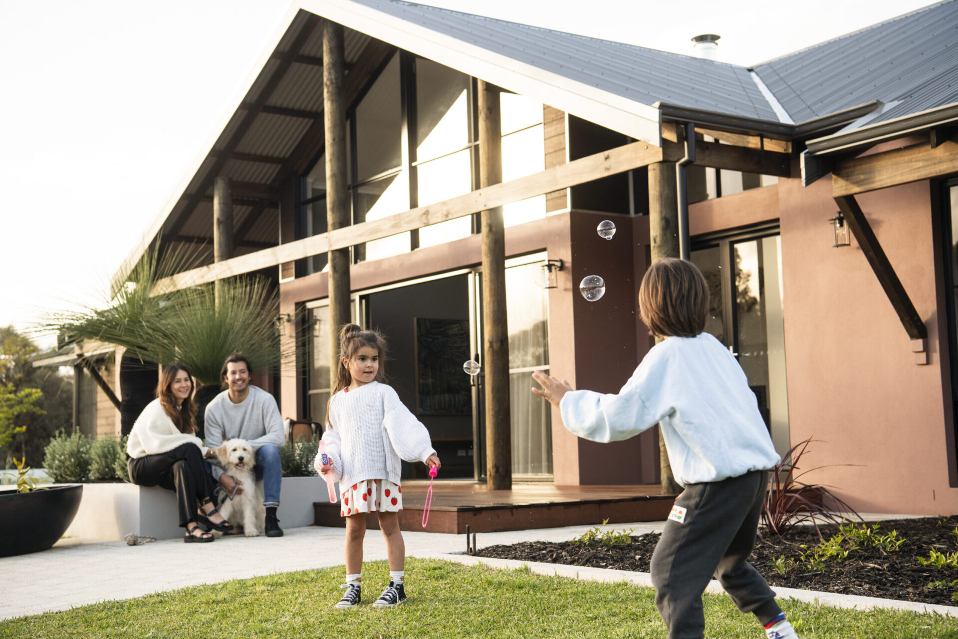 Family and children playing on the lawn outside their completed home