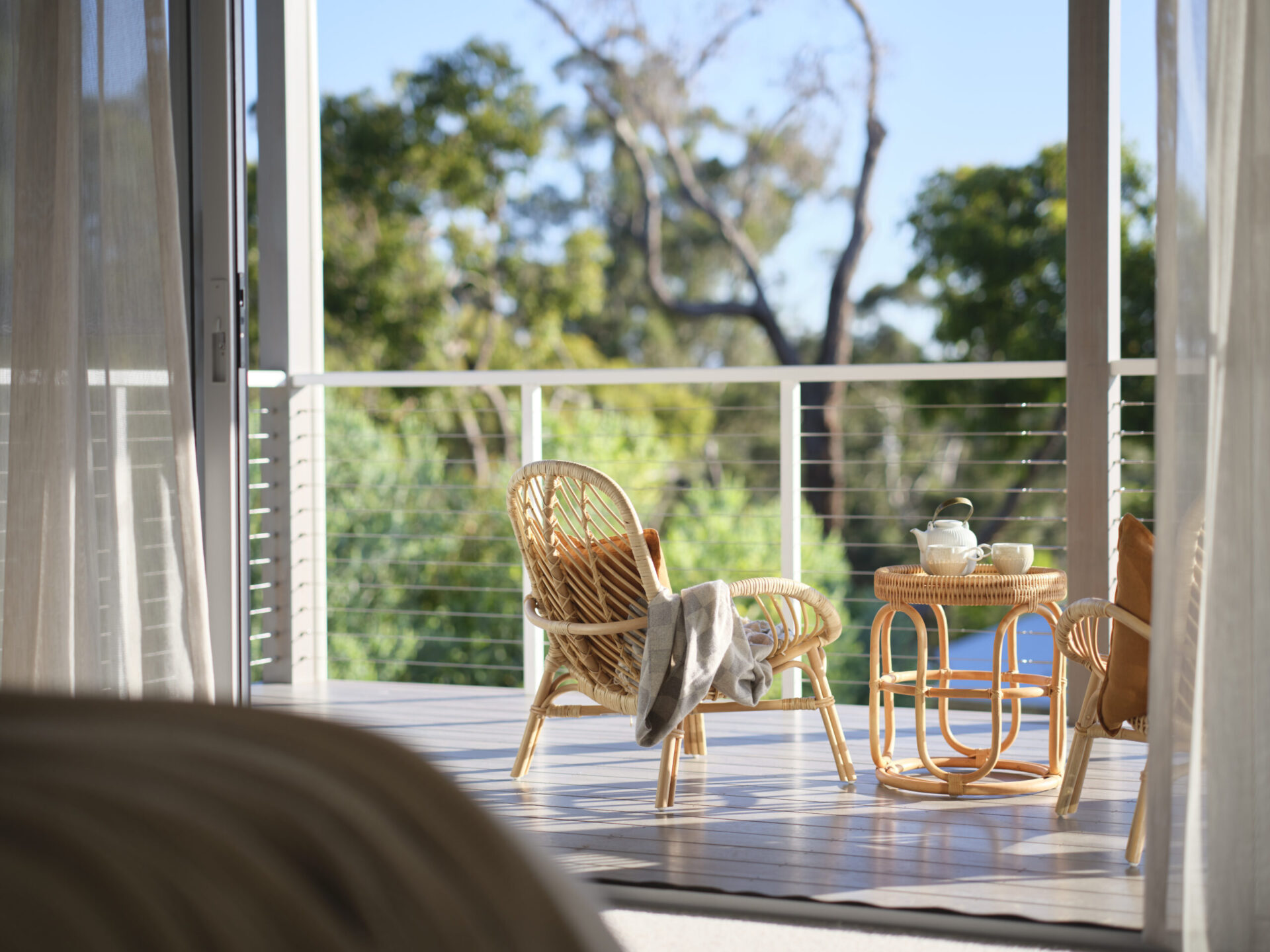 Balcony with rattan chairs and cable balustrade looking into bushland