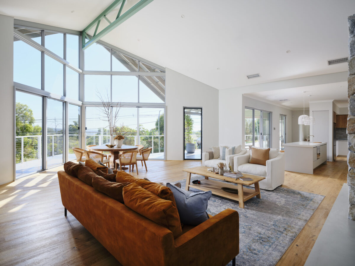 Living area with tan leather sofa, raked ceiling and full height glazing