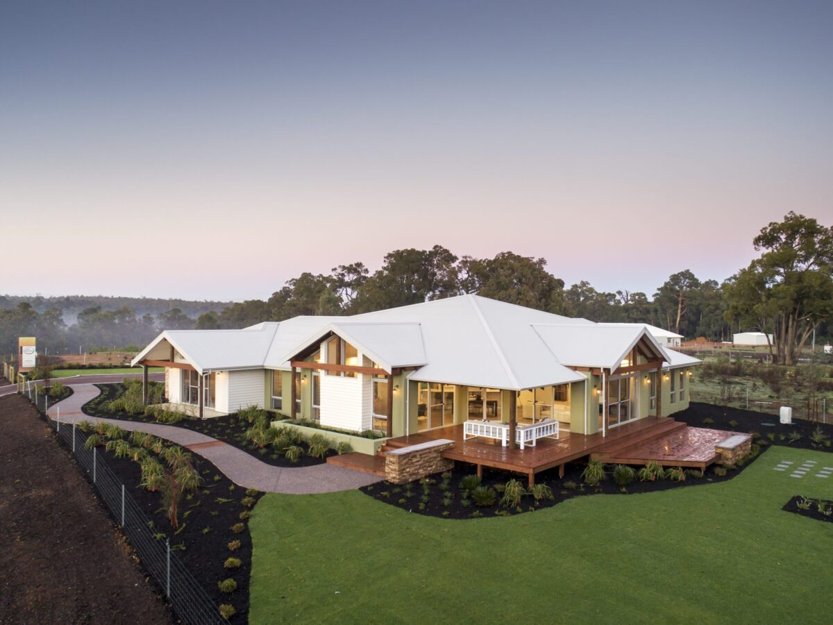 Homestead with wraparound verandah beside a landscaped dam and timber deck