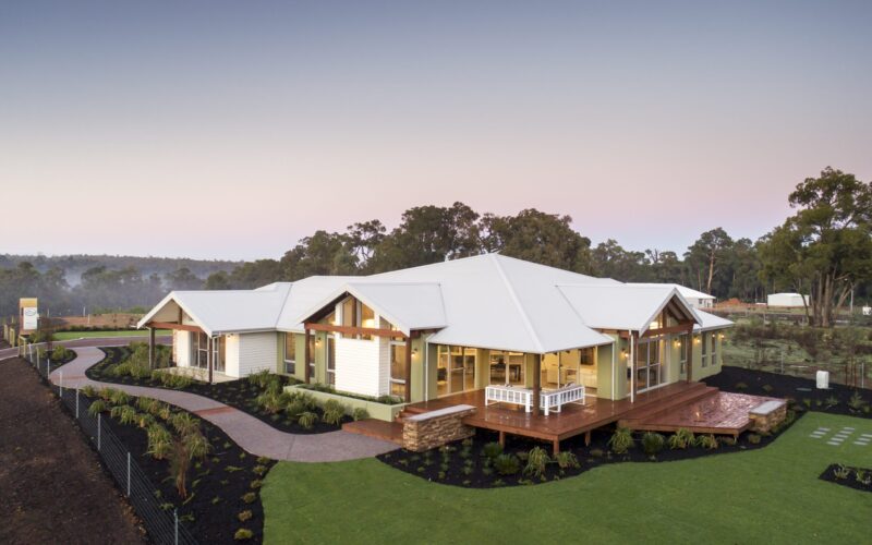 Homestead with wraparound verandah beside a landscaped dam and timber deck