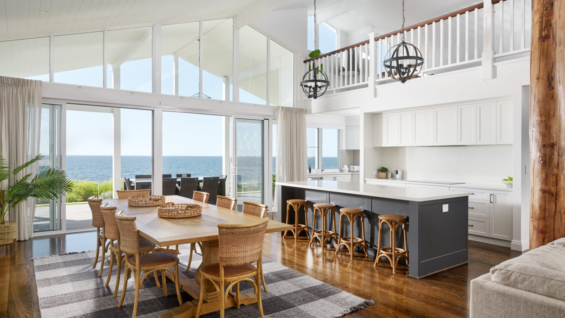 Dining and kitchen with rattan chairs, raked ceiling and ocean views