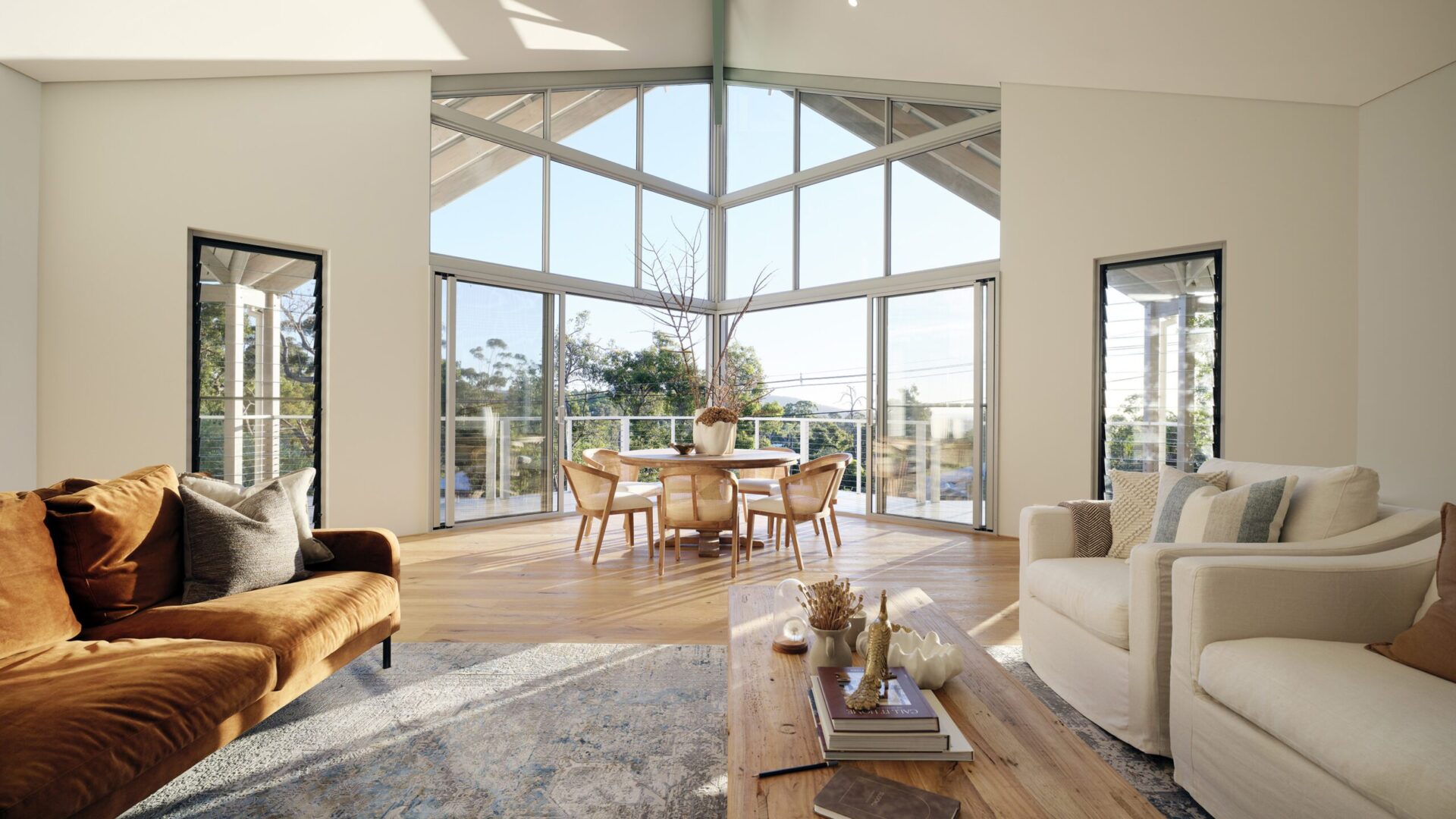 Living area with gable glazing, tan sofa and timber flooring