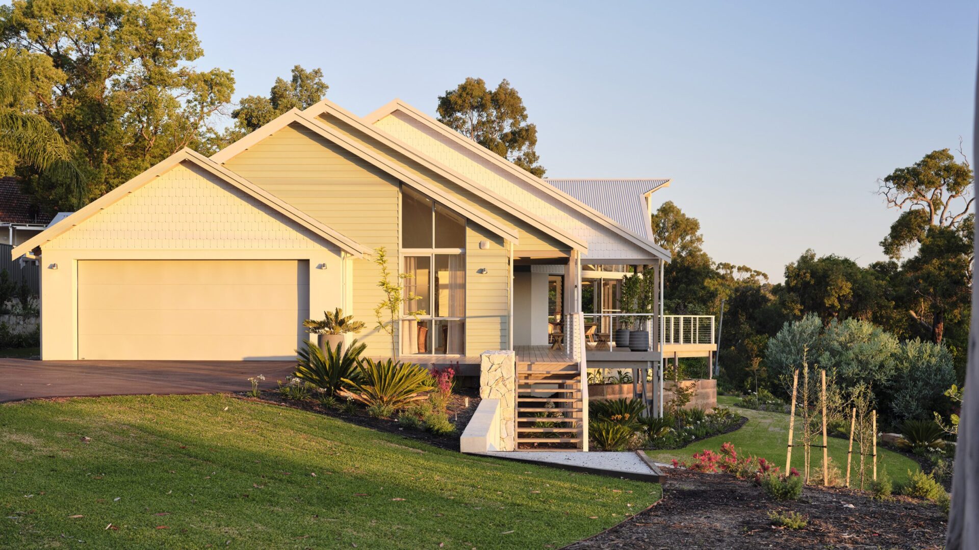Weatherboard home with gable glazing, double garage and native garden beds