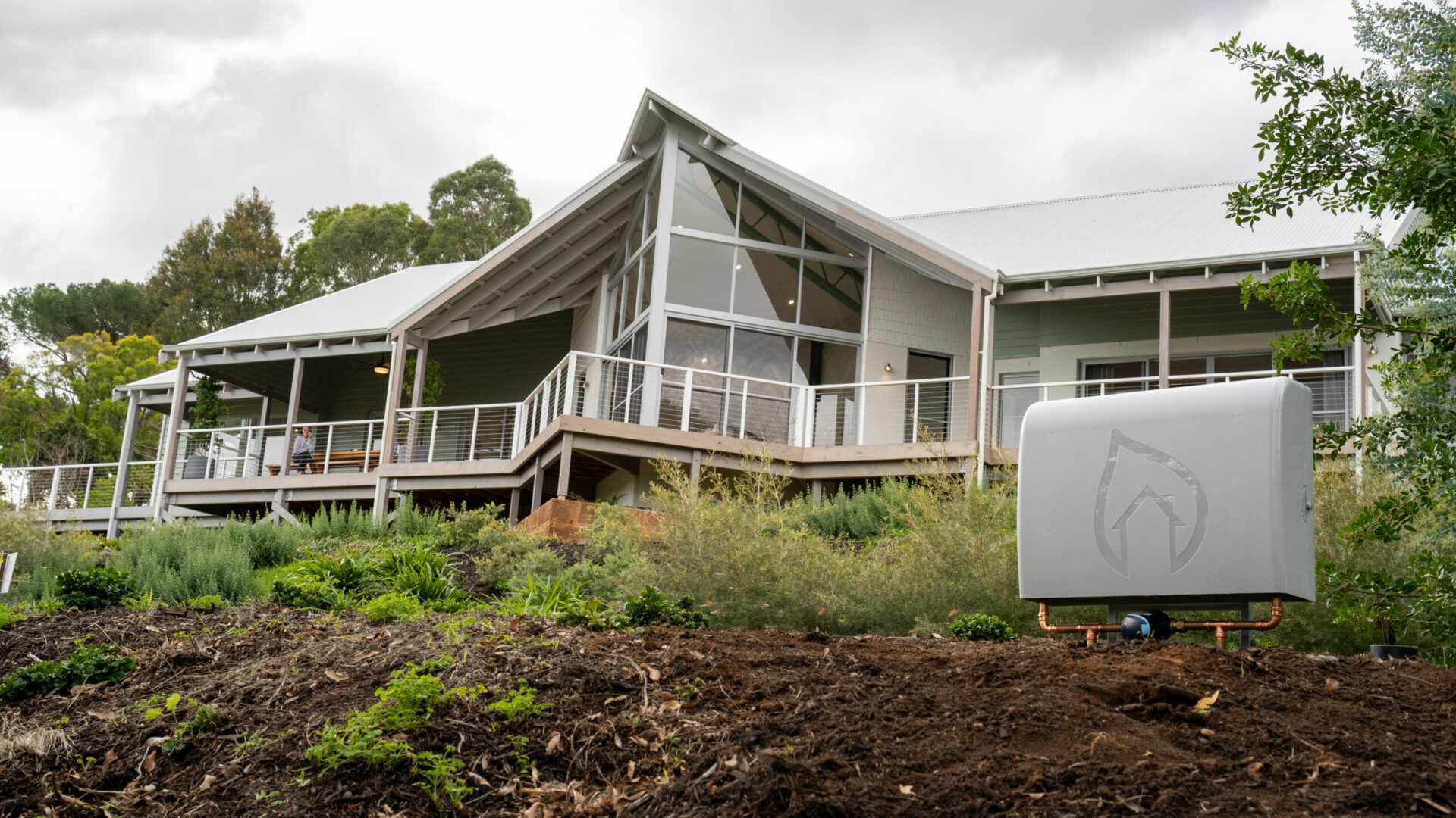 Home with gable glazing and wraparound verandah during landscaping works