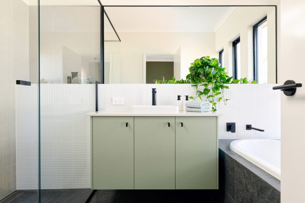 Bathroom with sage green vanity, black tapware and indoor plant