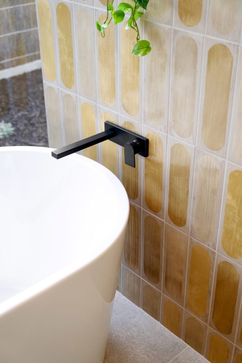 Freestanding bath against a terracotta tiled wall with black wall mounted tap