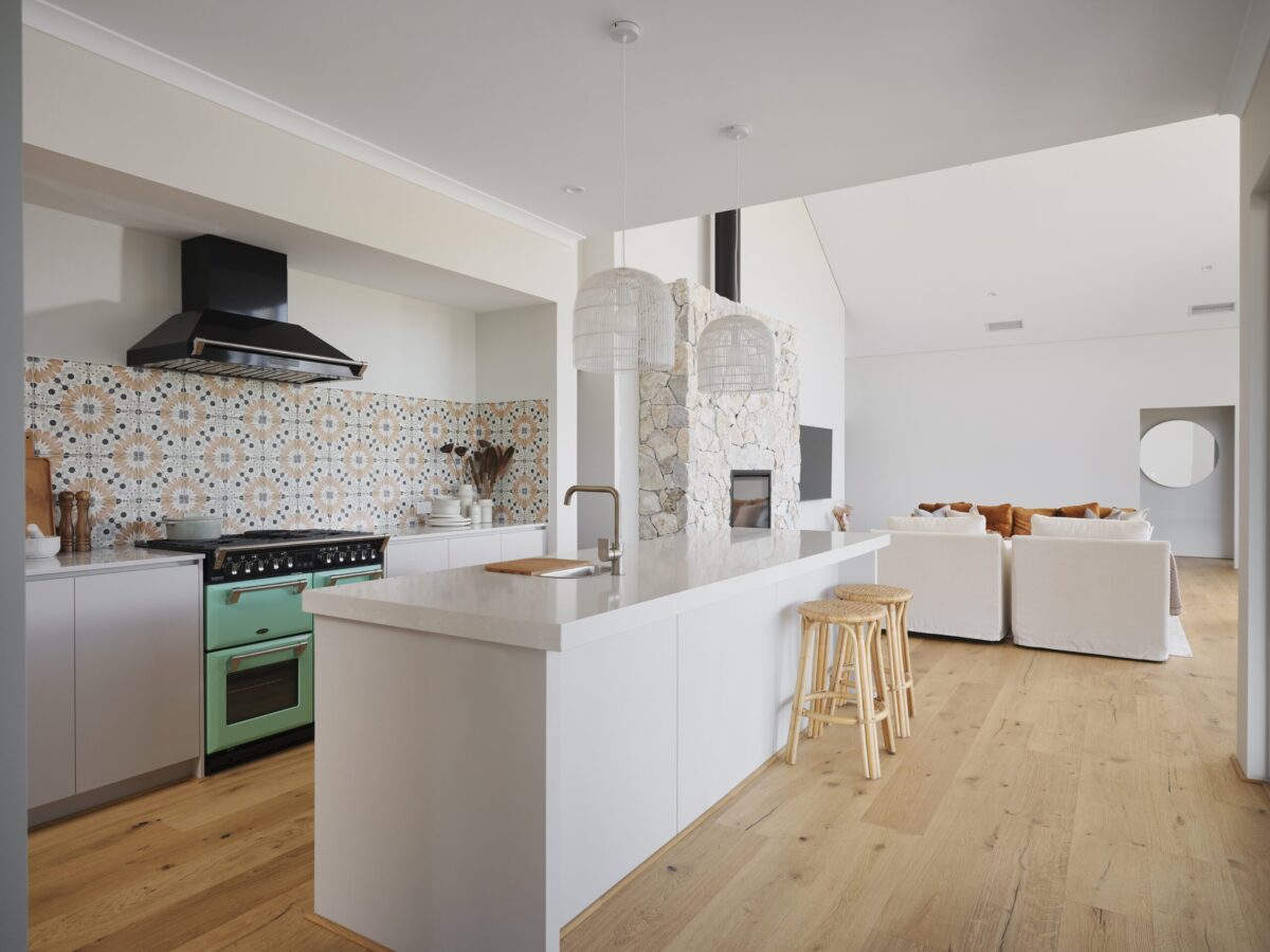 Kitchen with patterned tile splashback, white island bench and green freestanding cooker