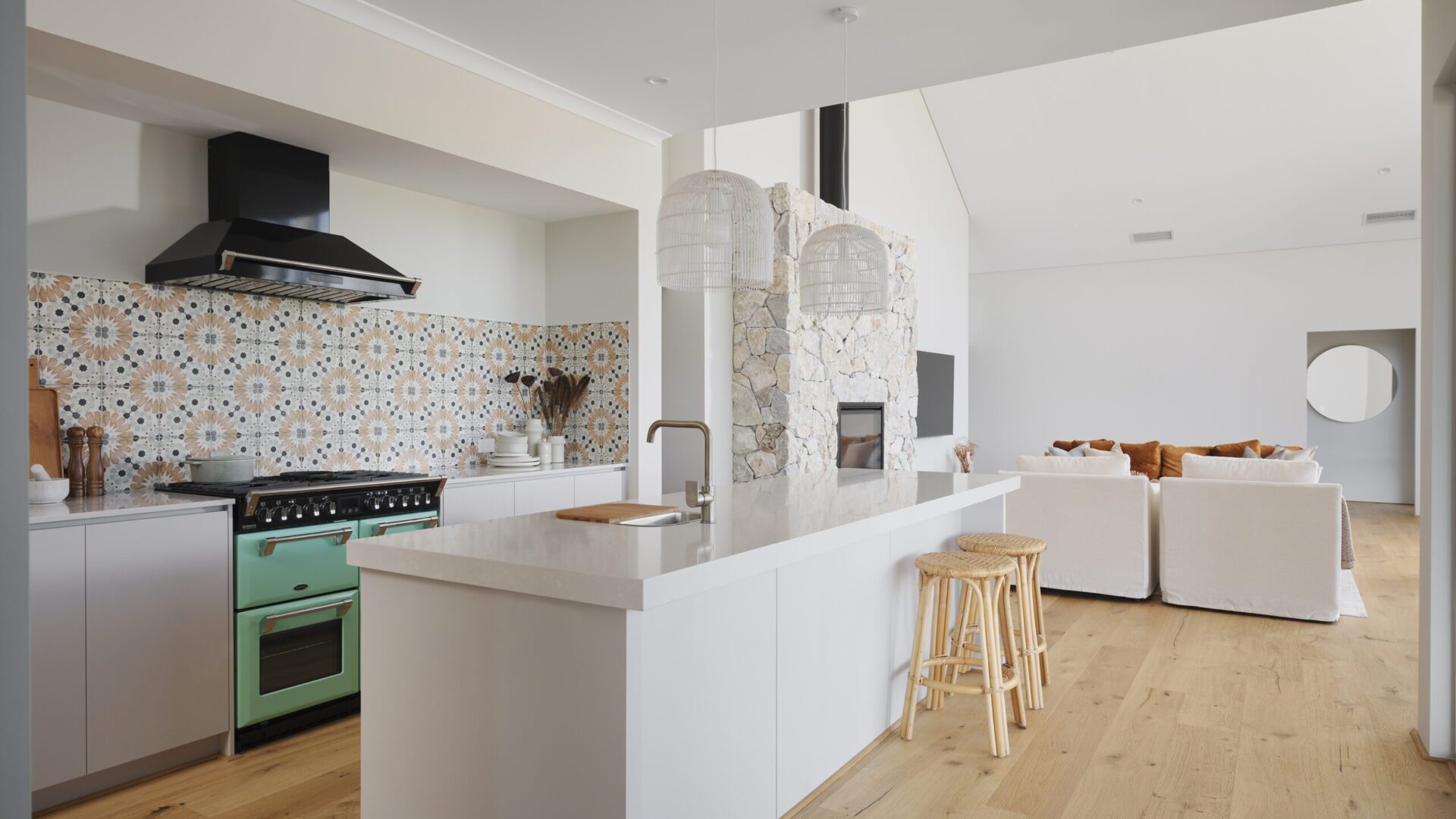 Kitchen with patterned tile splashback, white island bench and green freestanding cooker